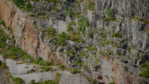 Group of people climbing cliff.