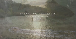 Poster for film with person in middle of body of water with mountains in background.