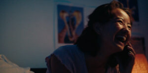 Person in phone in low light looking right and smiling.