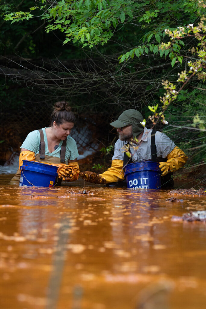 People in brown water with gloves and wadders 