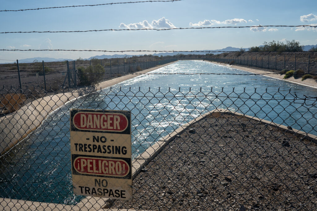 Waterway behind fence with sign that says "danger" and "no trespassing" 