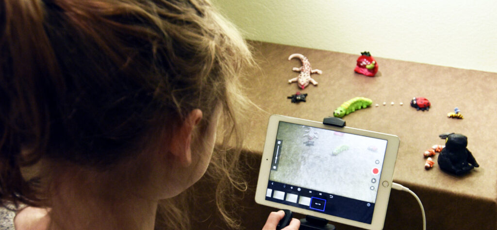 Person with stop motion tablet and figures