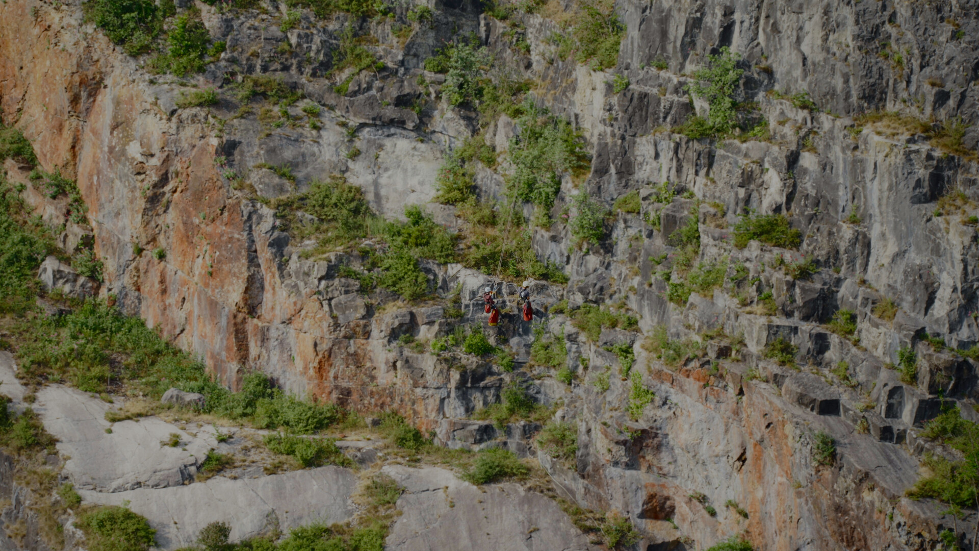 Group of people climbing cliff.