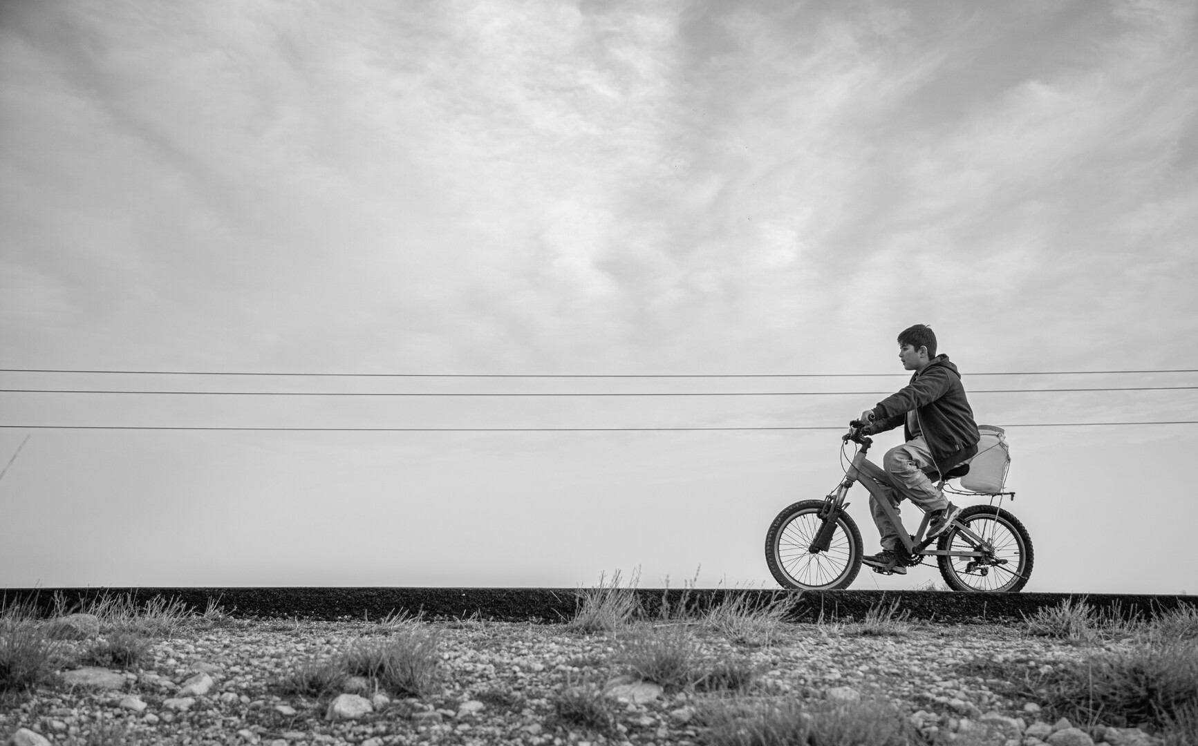 Grey scale image of person riding bike.