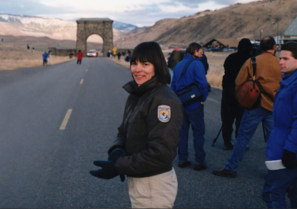 Screenshot Person looks back towards camera by Yellowstone archway.