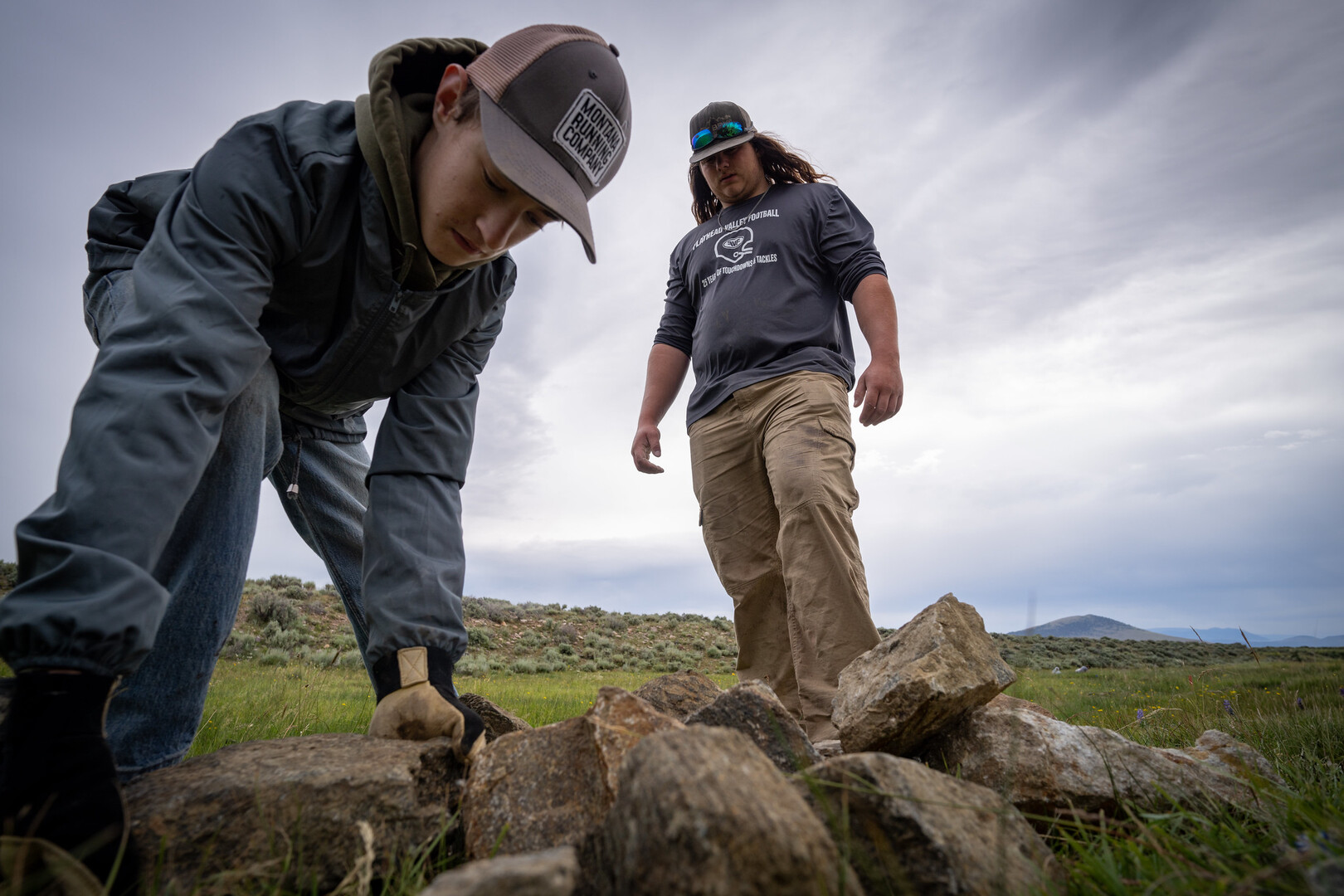 Two people look down towards pile of rocks.