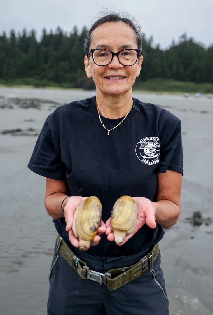 Person stands with clams in hands.