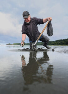 Person kneels in water with tools.