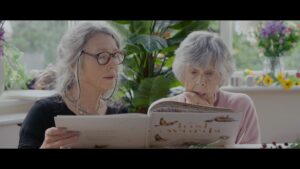 Two people sit inside and look at book.