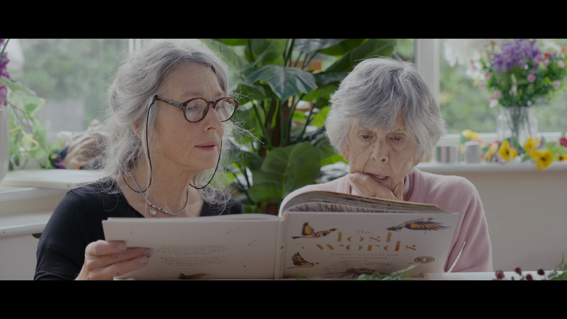 Two people sit inside and look at book.