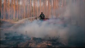 Person with firehose in forest.