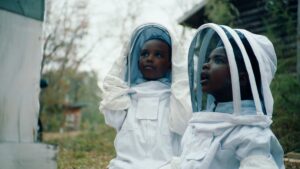 Two kids in beekeeping suits.