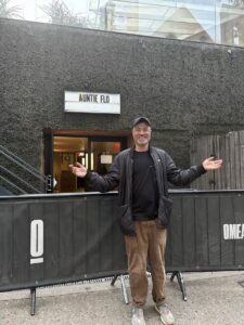 Person standing outside with arms outstretched.