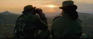 People sit with binoculars in low light.
